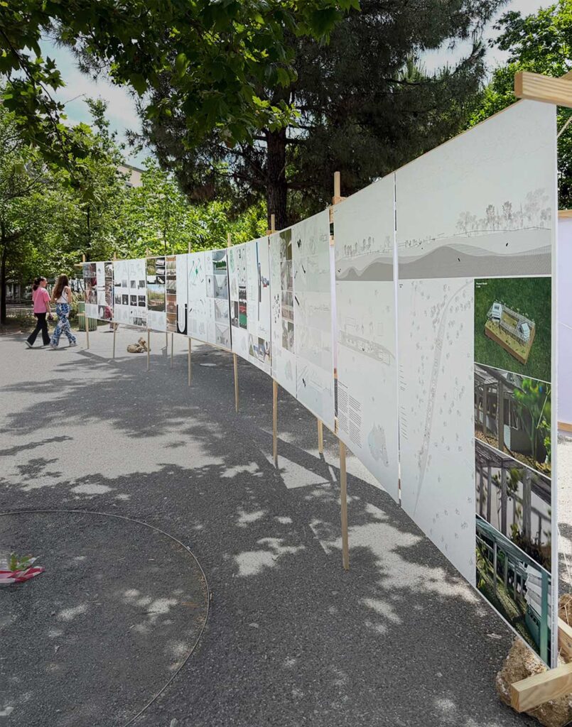 People outside under trees in a plaza looking at mounted drawings.