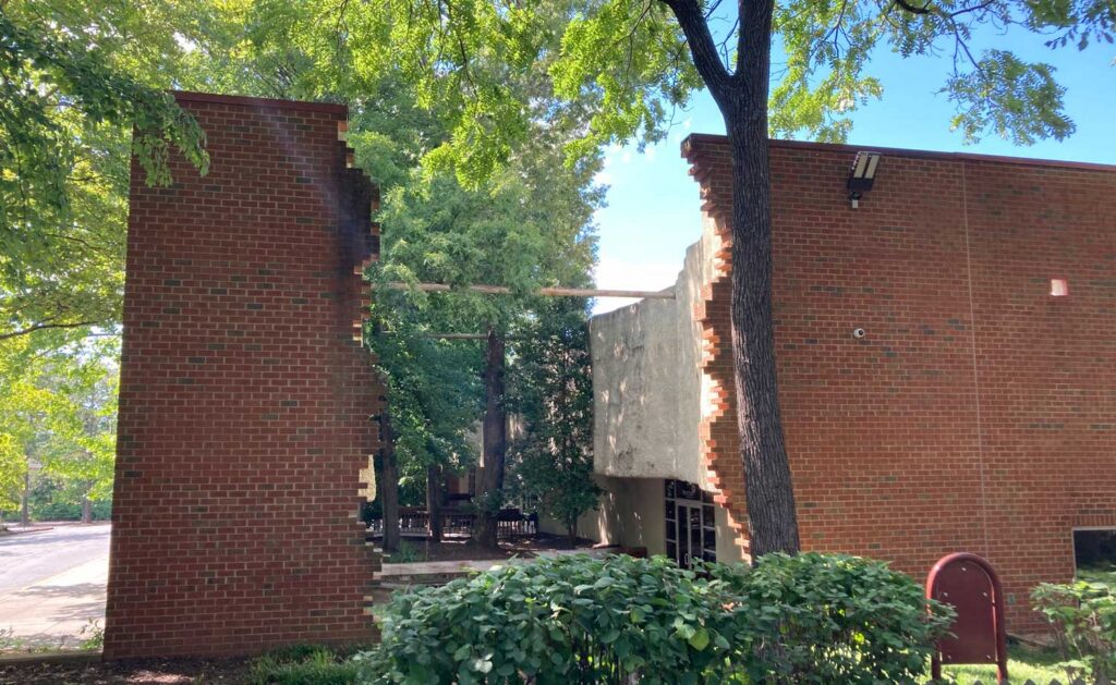Brick building with jagged edges and trees.