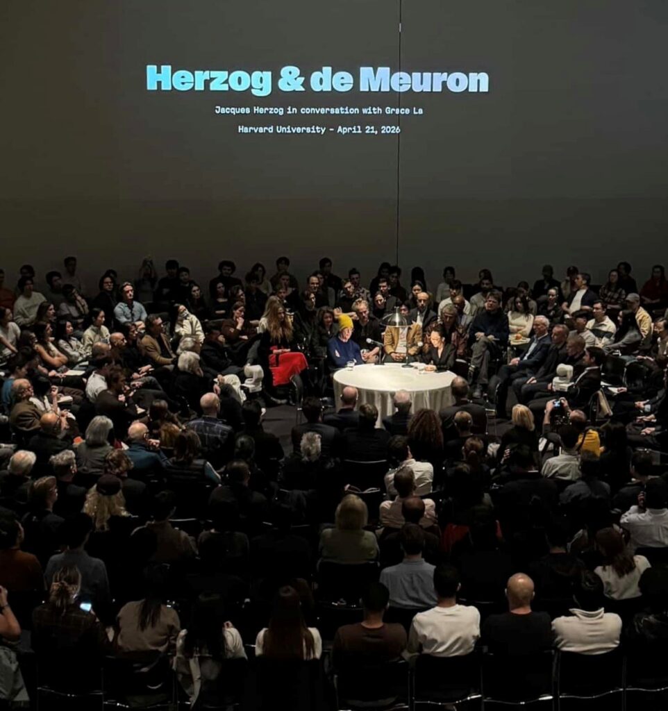 Audience seated around a central round table during a talk titled “Herzog & de Meuron.”