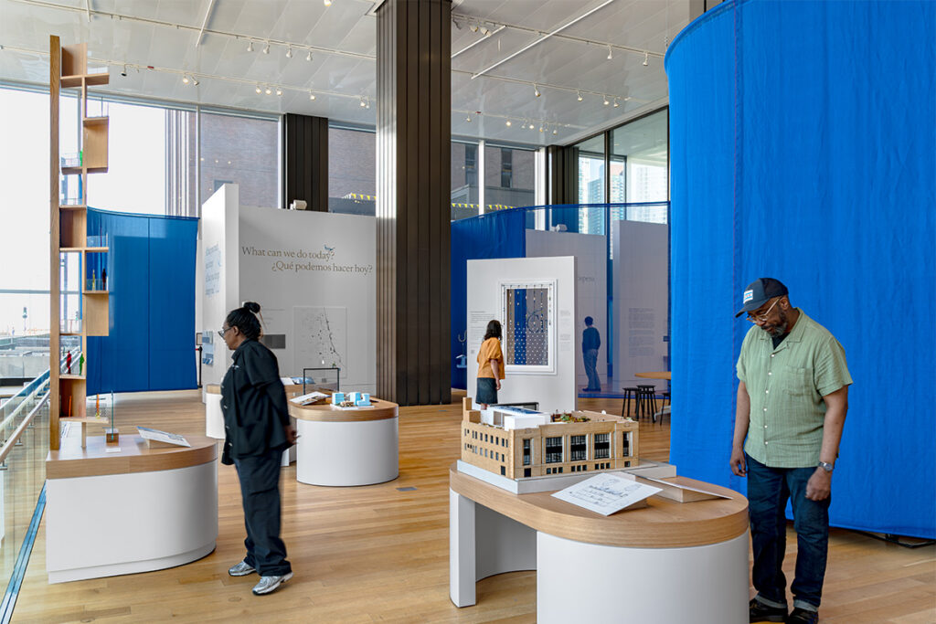 Visitors look at models and media in gallery