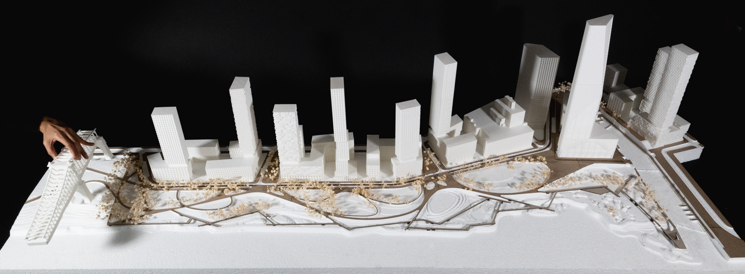Large site model in white and wood against black background.