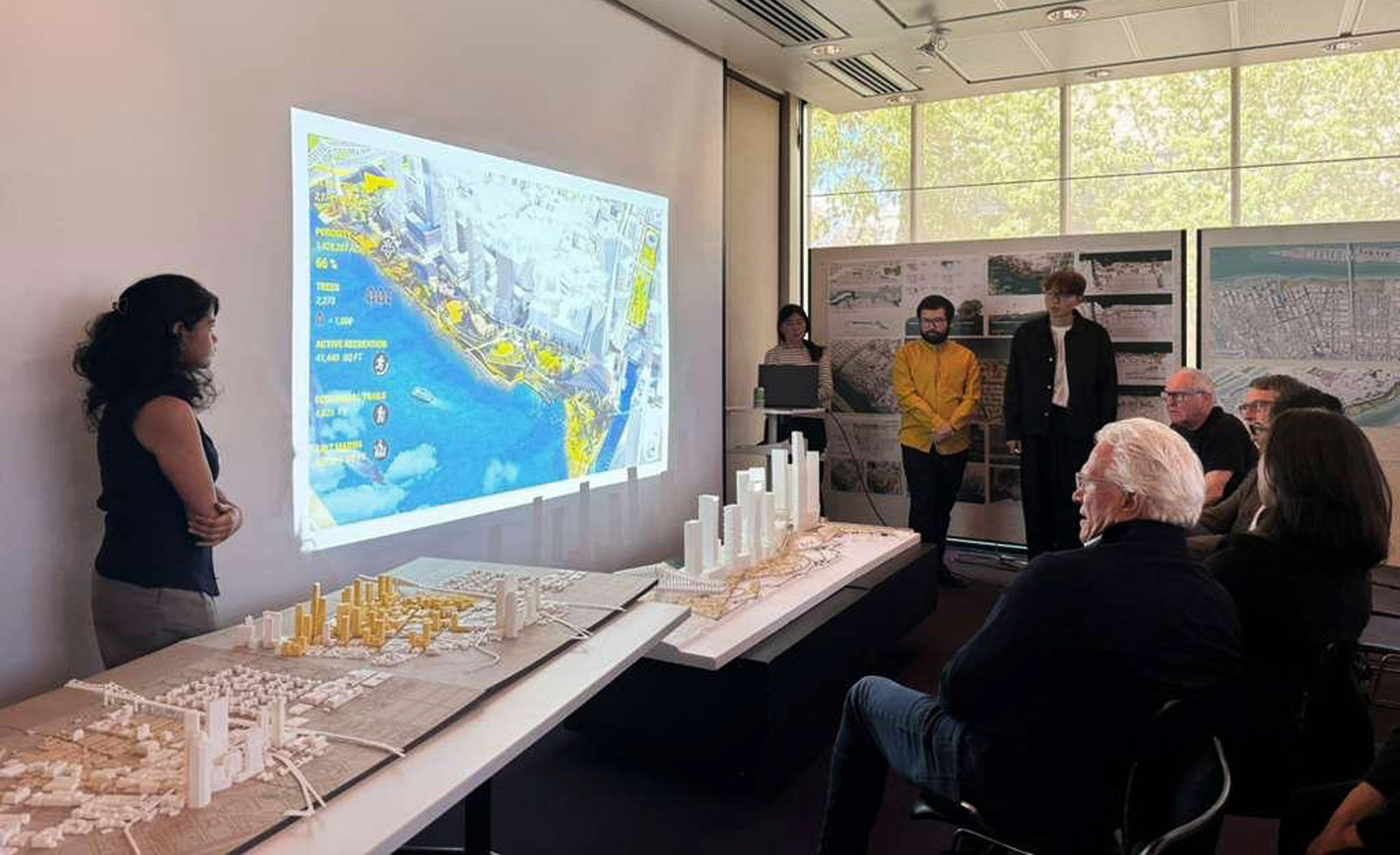 People watching a student presentation with projected map and models.