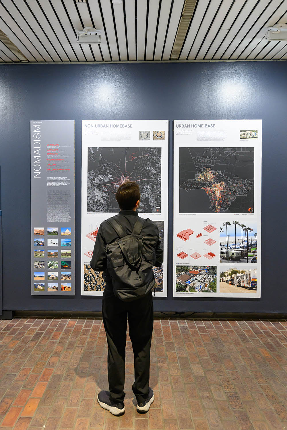 A person reading on of three large panels of maps and photos.