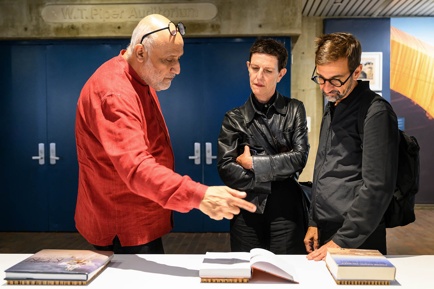Three people intensely discussing a selection of books.
