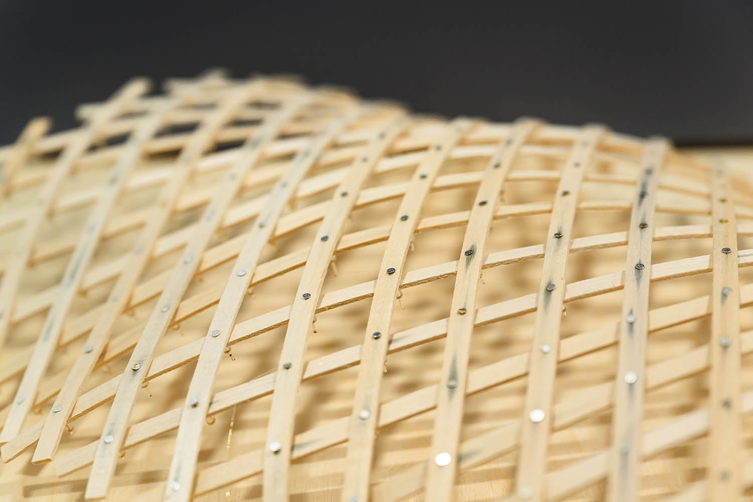 A model of a diagrid structure, made of wood and small nails.
