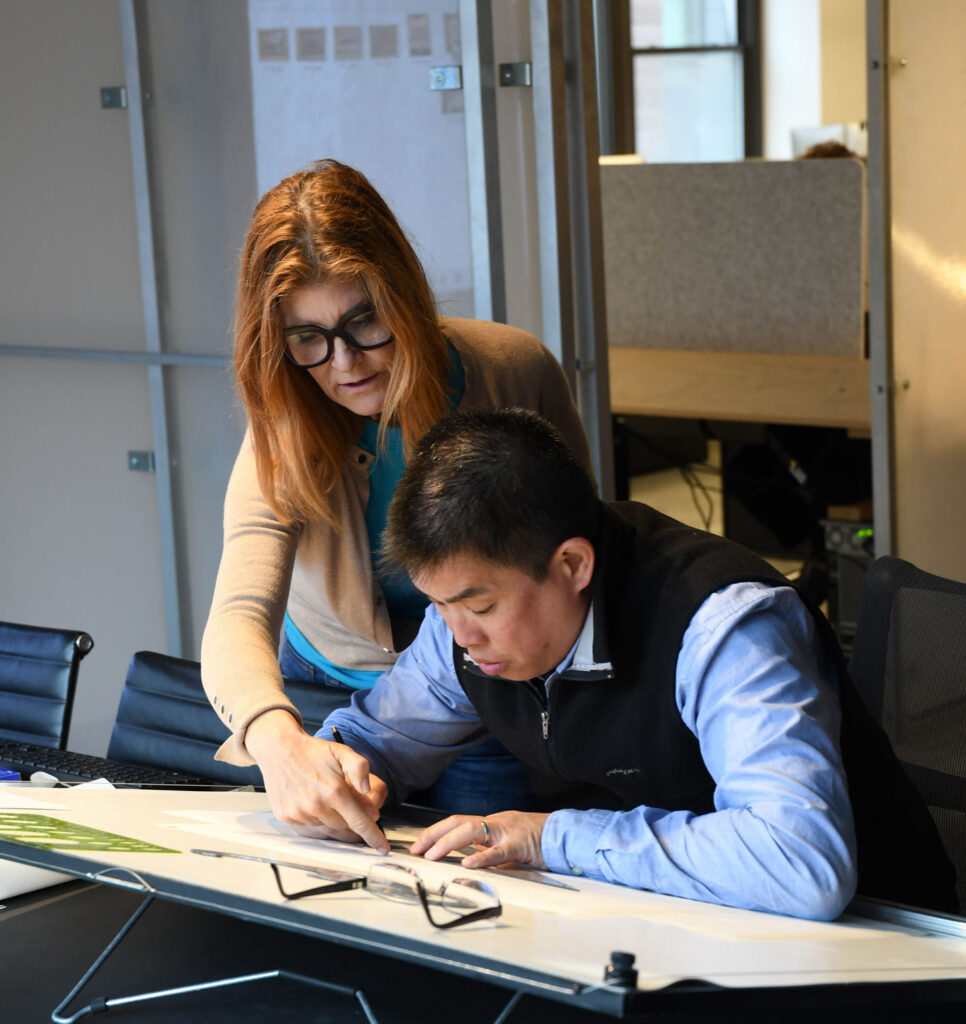 Woman leaning over a man at a desk.