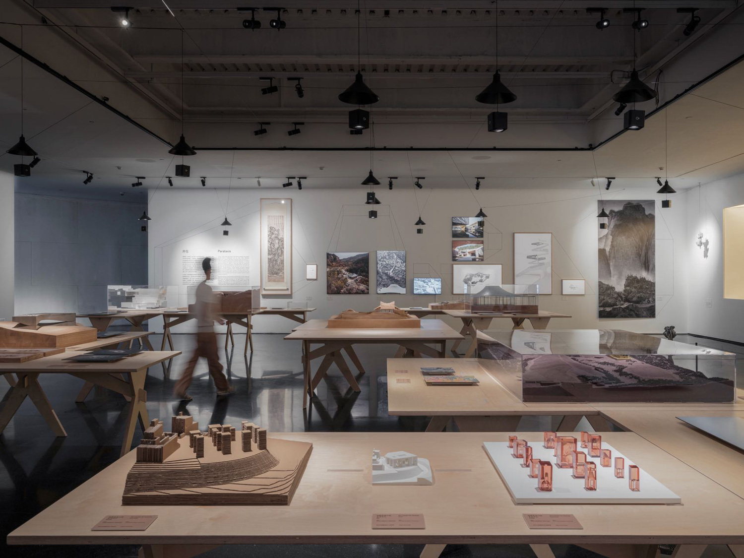 View of exhibition space with figure walking through it.