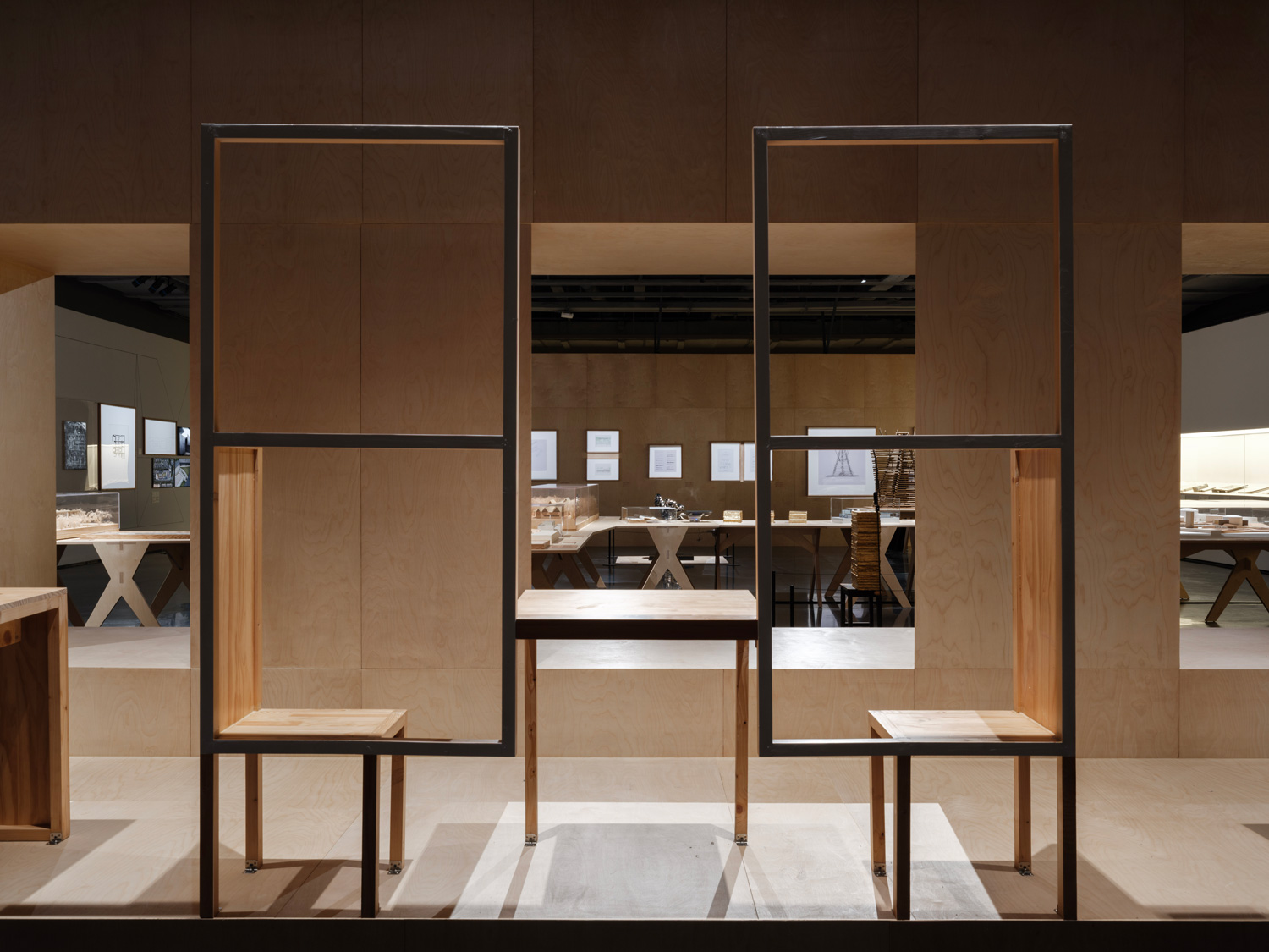 View of two stools and table in exhibition space.