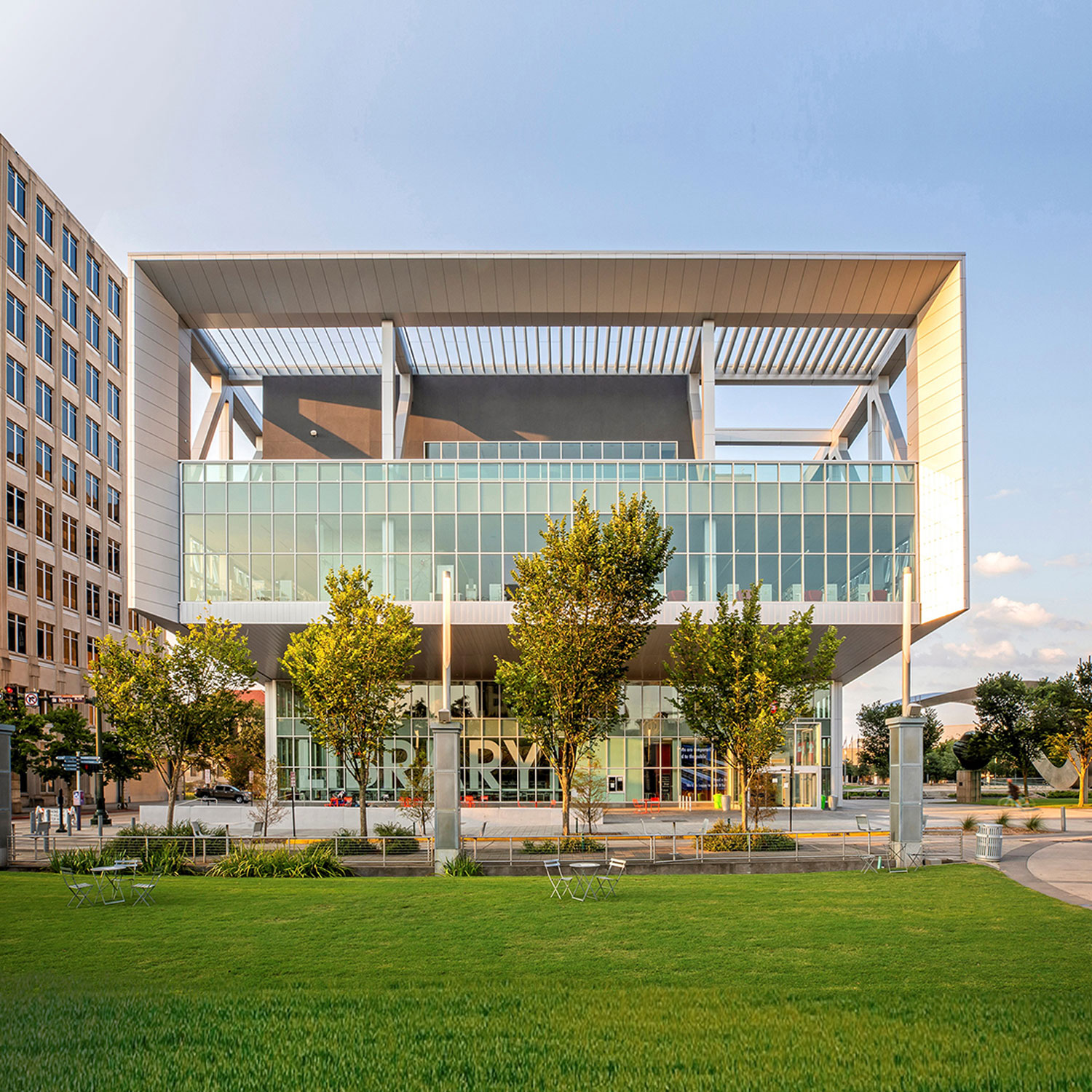 Exterior of a modern looking building with grass and trees.