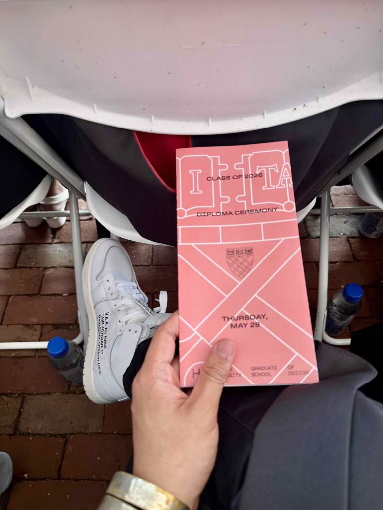 A photograph from the perspective of a person holding a diploma ceremony program and wearing sneakers designed by Virgil Abloh.