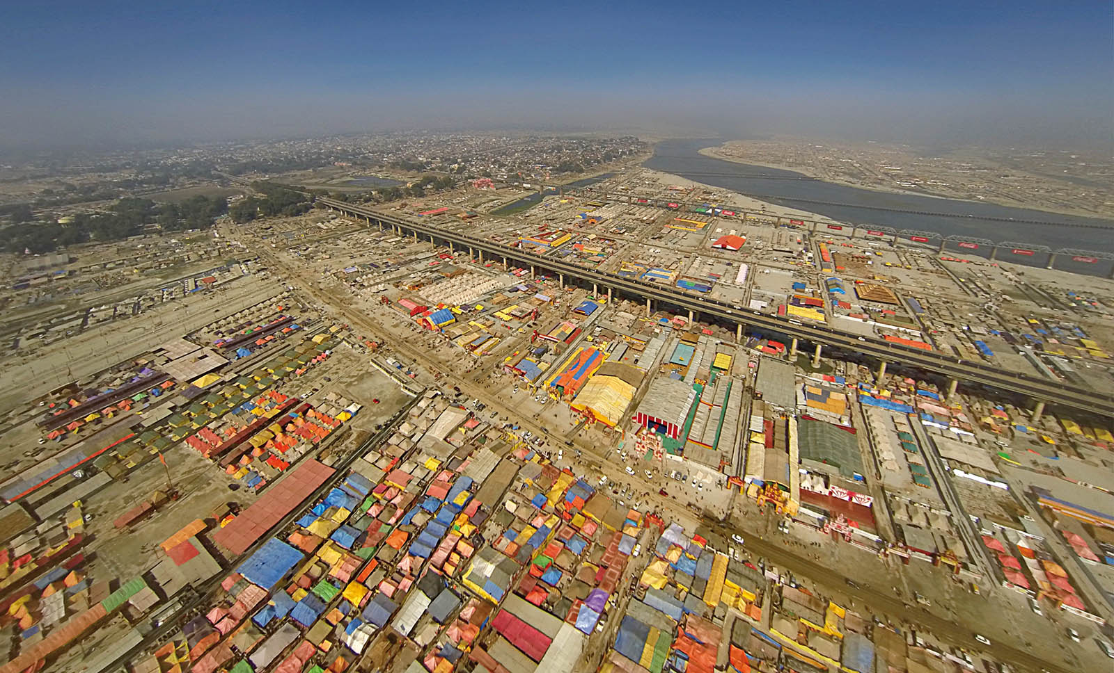 Aerial view of a vast colorful temporary city surrounding a river