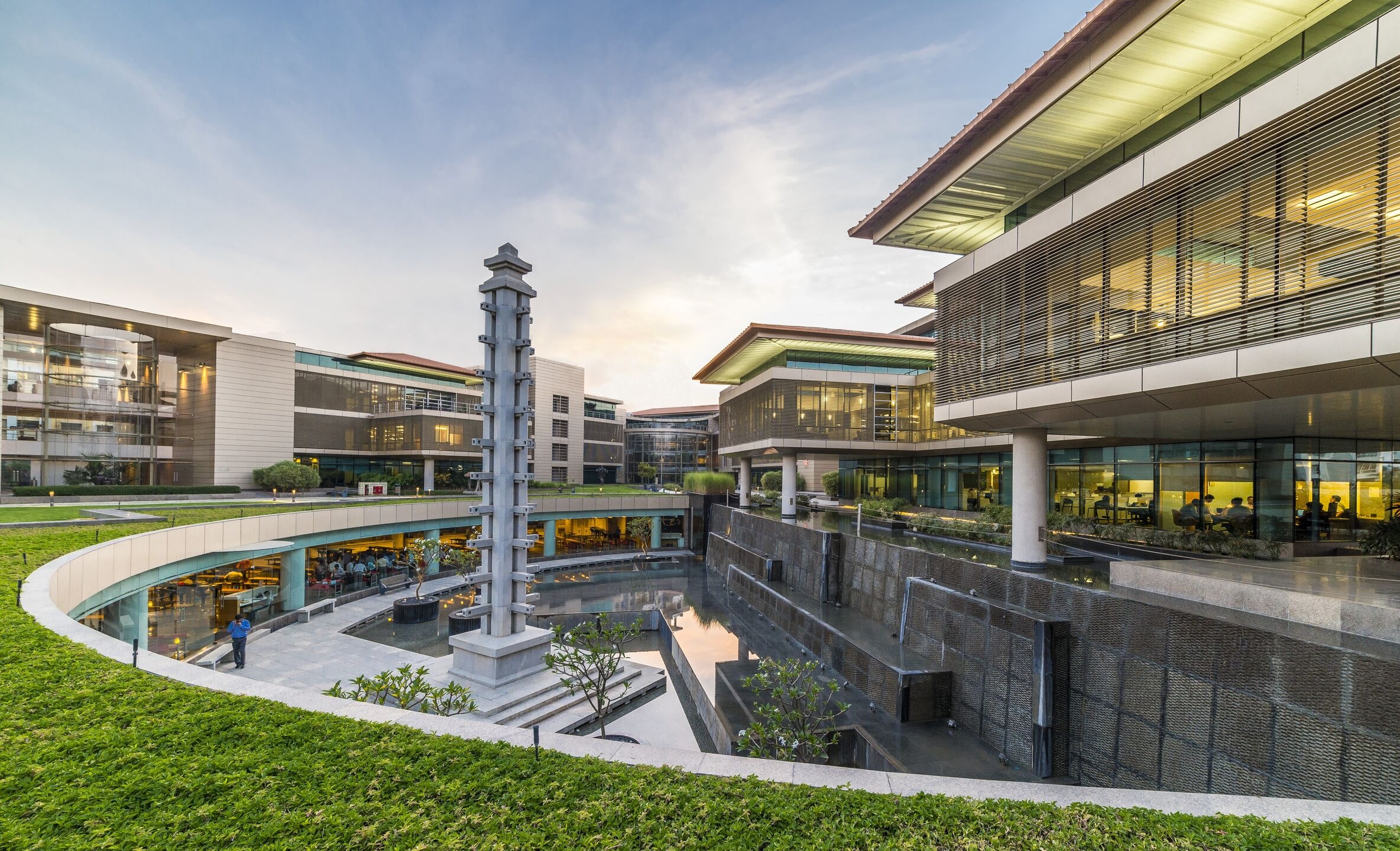 Suzlon One Earth Global Corporate Headquarters in Pune at dusk with multiple glass and steel buildings surrounding a sunken courtyard.