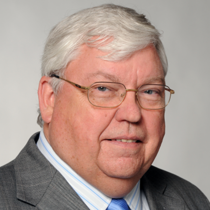A head-and-shoulders portrait of Karl-Werner Schulte, an older man with white hair and glasses, wearing a gray suit and striped shirt against a plain light gray background.