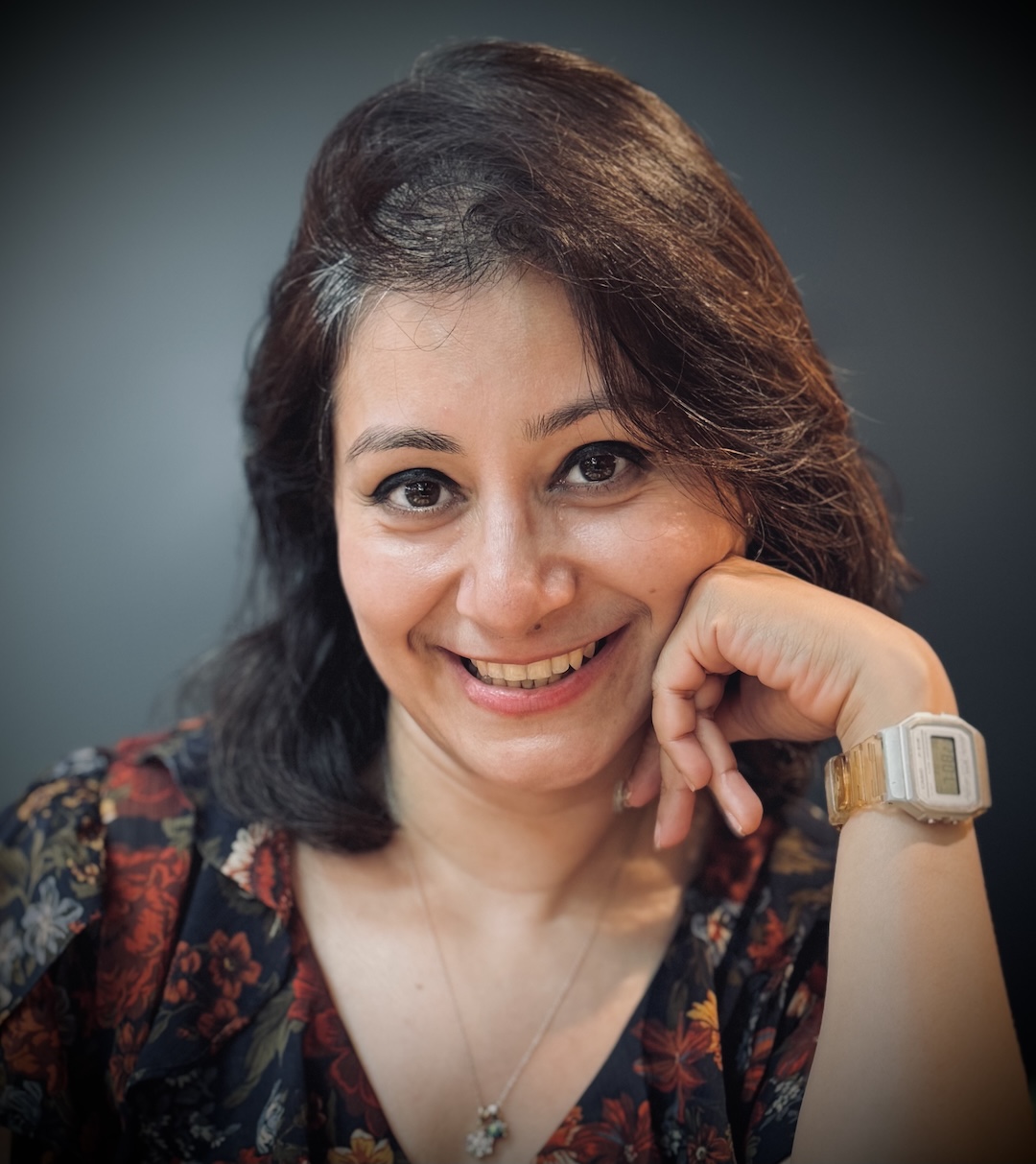 Smiling woman with dark hair wearing a floral-patterned top.