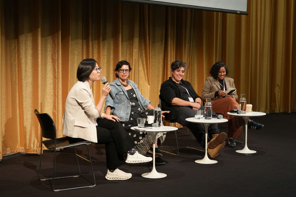 A panel of four people sits in chairs in Piper Auditorium.