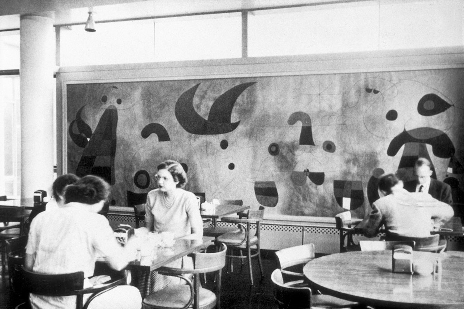 People sit at a table in front of a large wall mural.