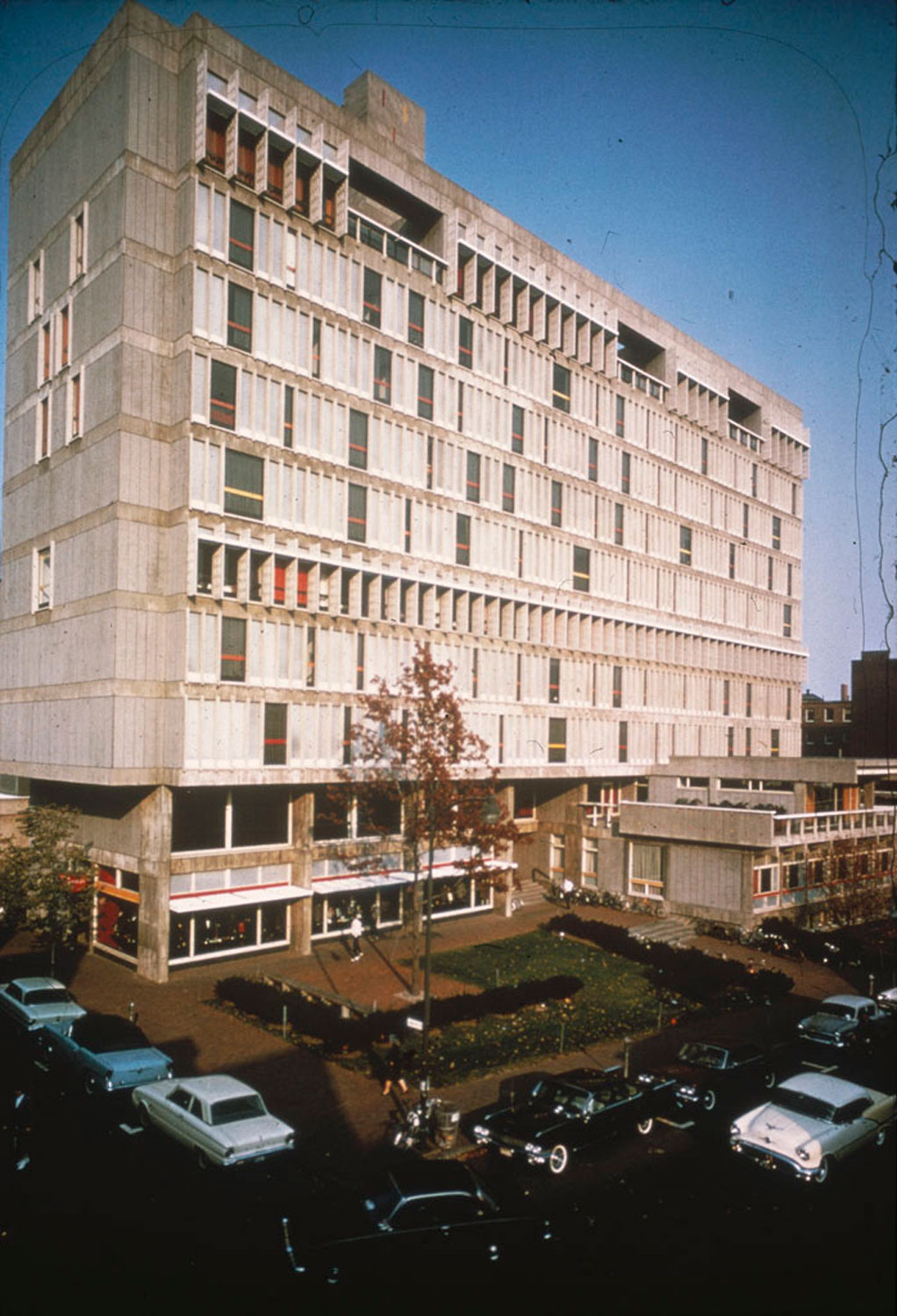 Tall concrete building with ground level patio and colorful panels.