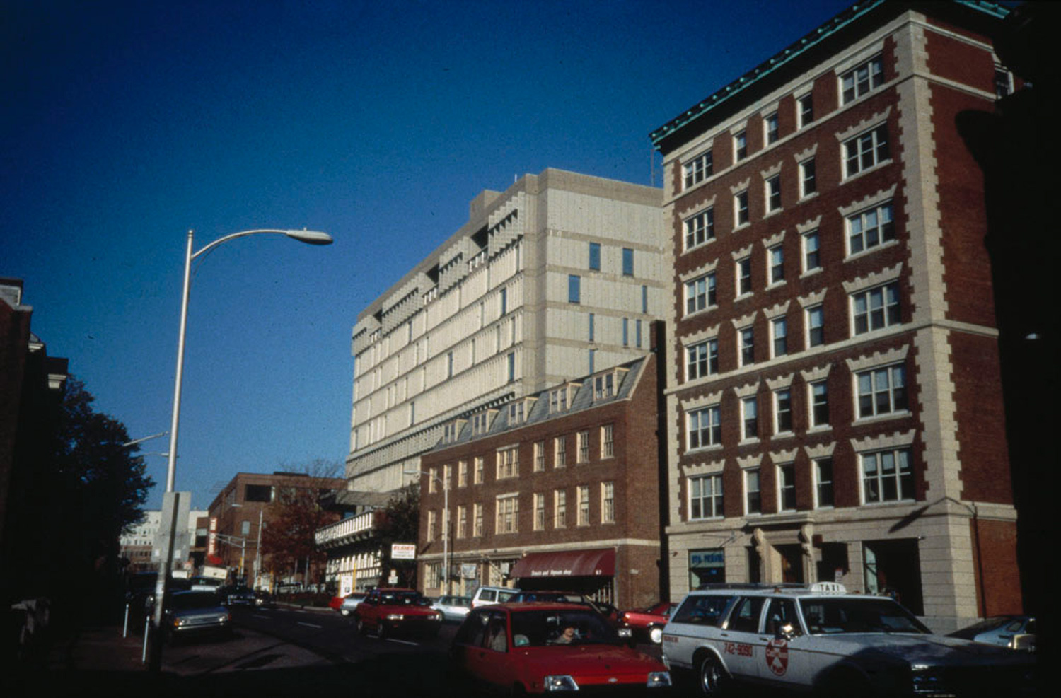 Brick building surrounding a taller concrete building.