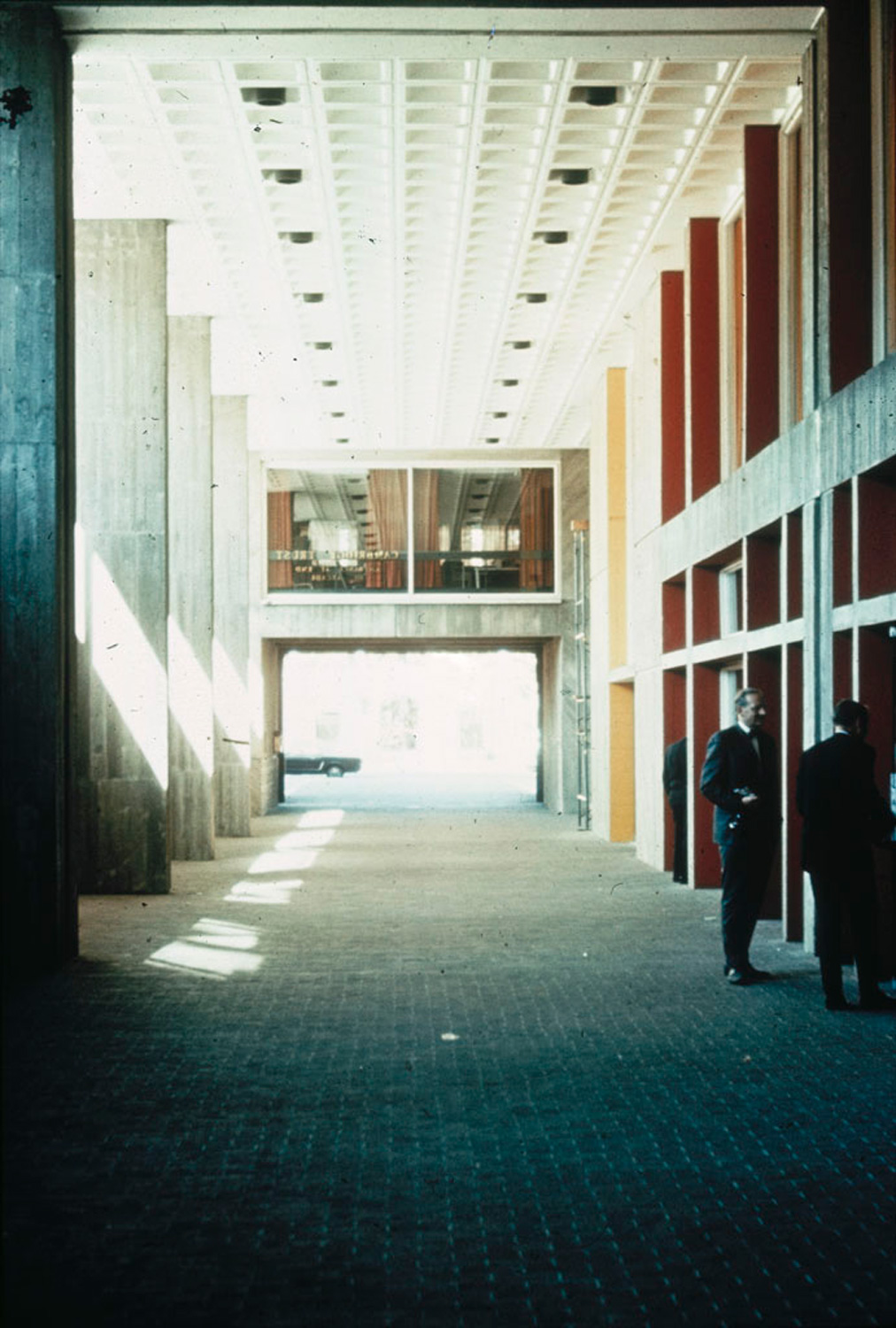 Interior walkway that cuts through a concrete building with natural light coming in.