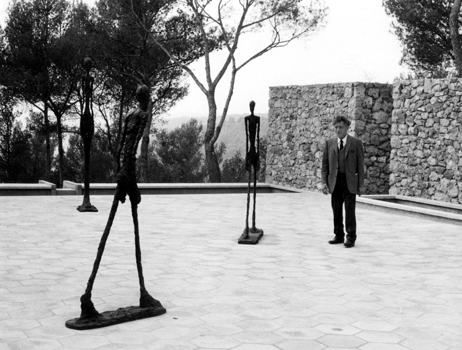 Statue court with three Giacometti-like statues and a man.