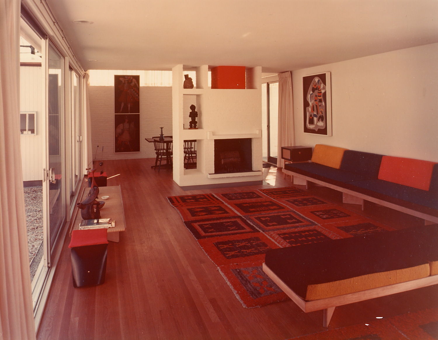 Living room with fireplace, white walls, sliding glass doors, and bright colors throughout.t