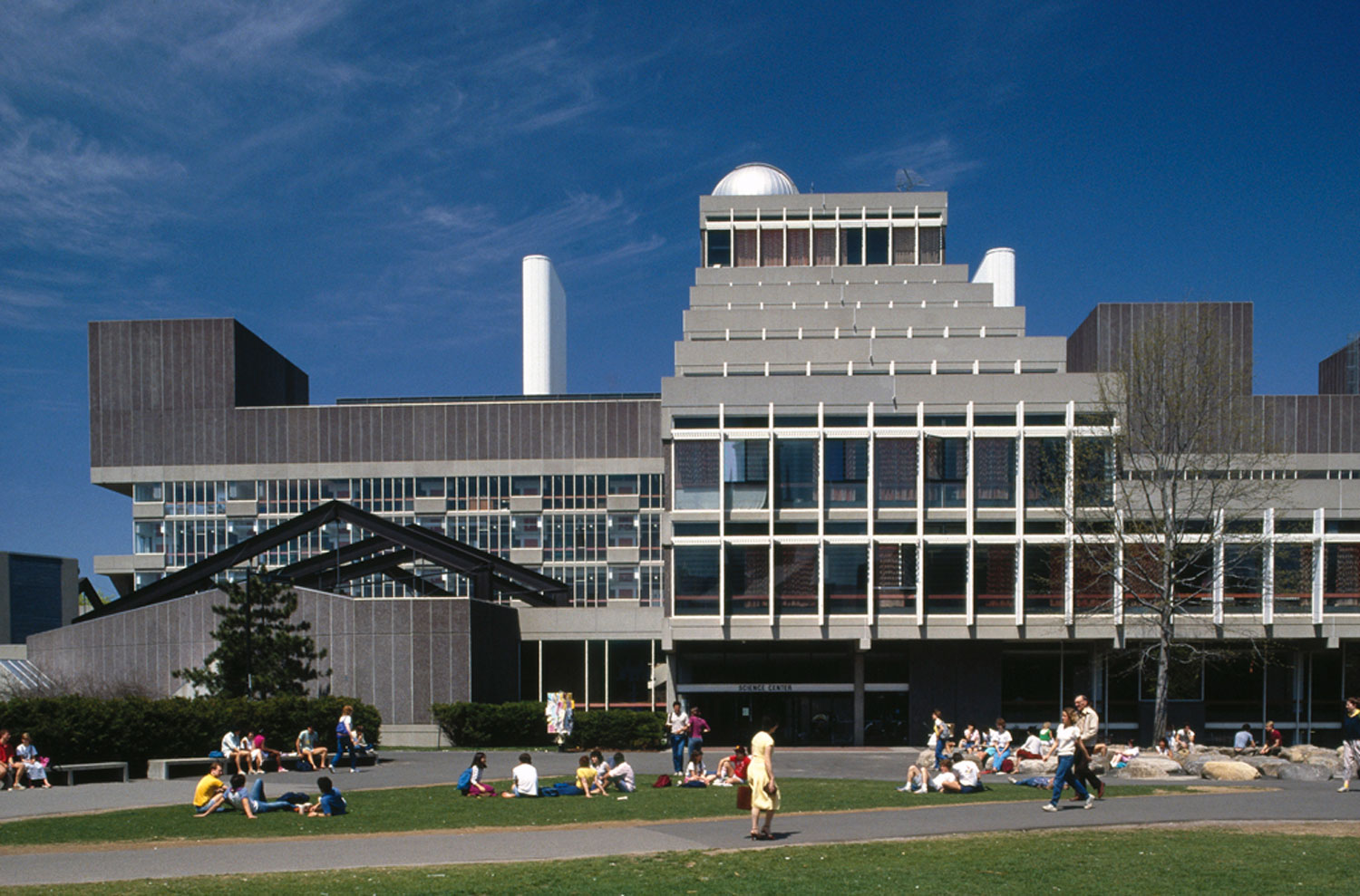 Modern concrete and glass building that steps upward toward a dome like structure.