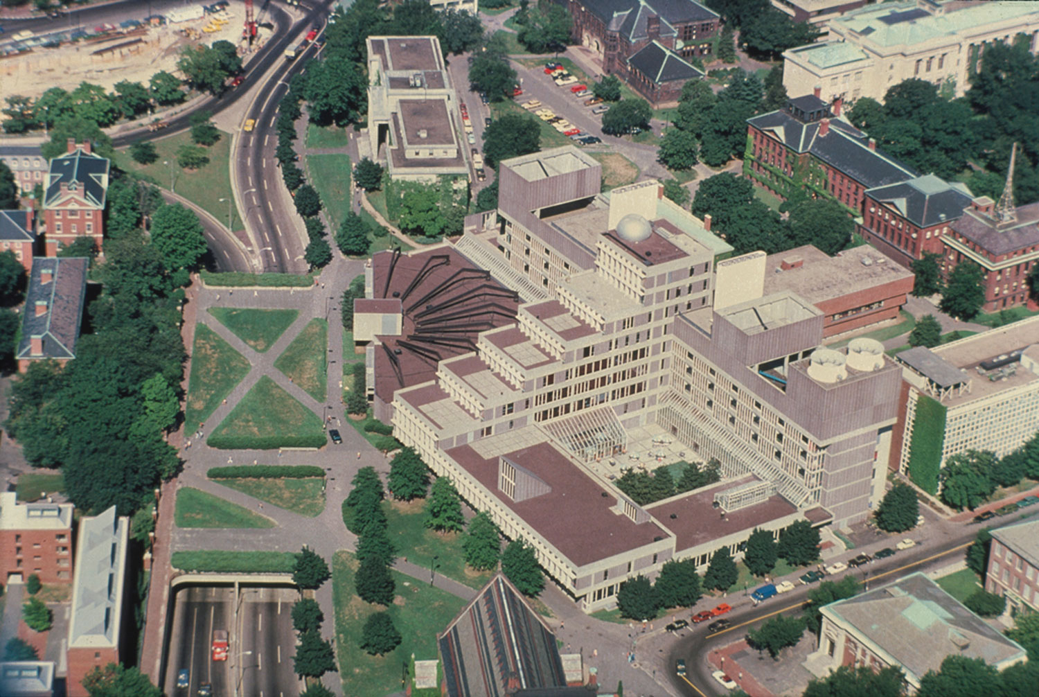 Aerial image of large stepped building with radial front feature.