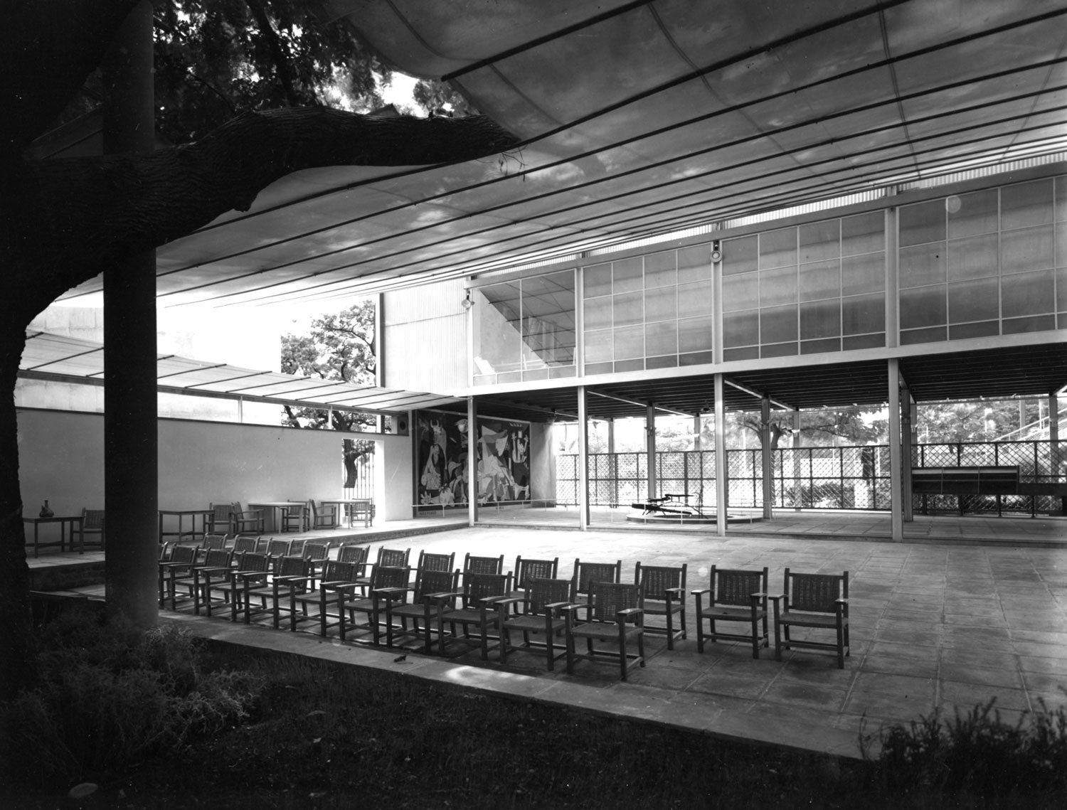 Inside hall with chairs, high ceilings, and glass.