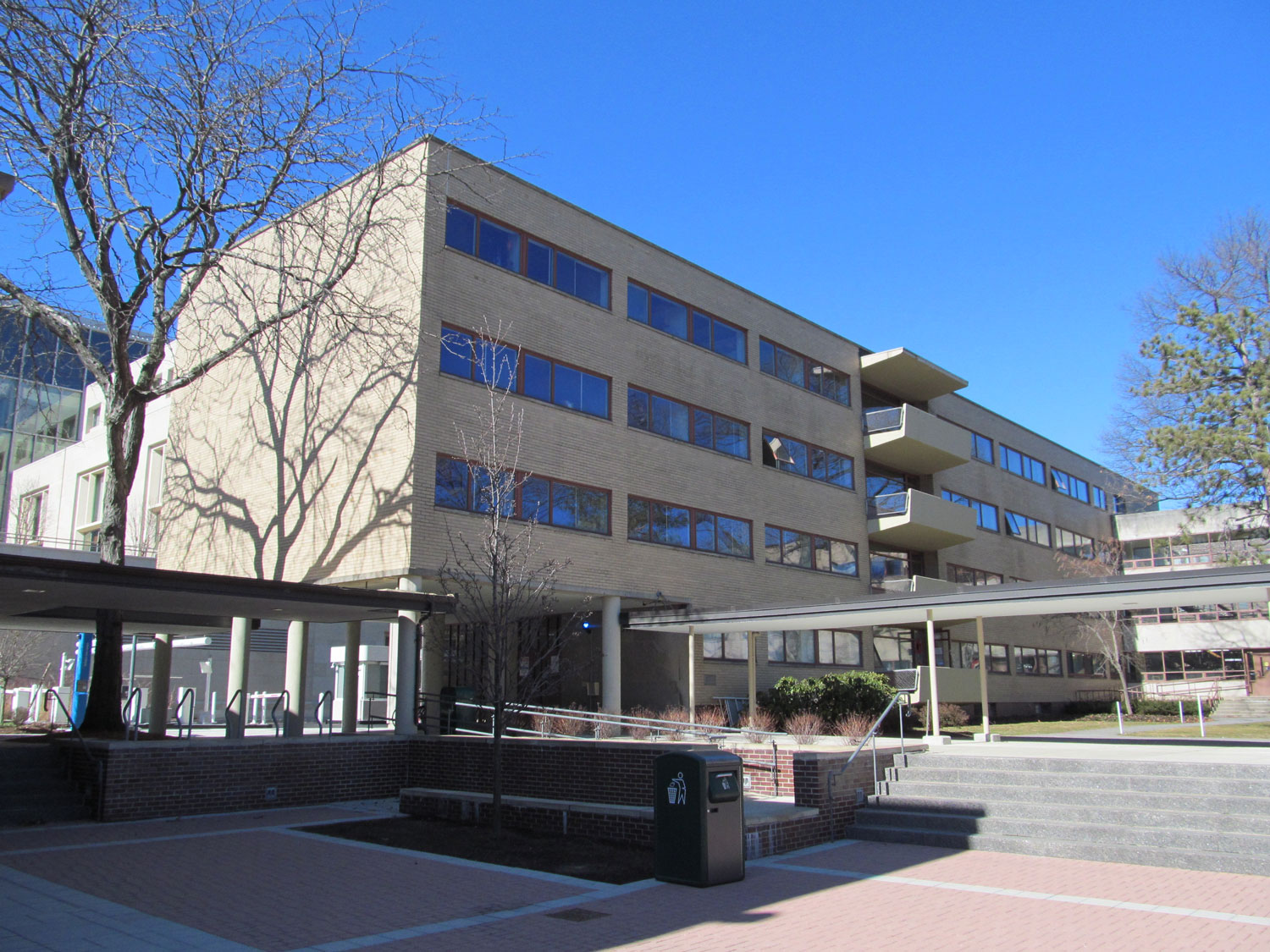 Tan modern building with courtyard, stairs, and covered walkways.