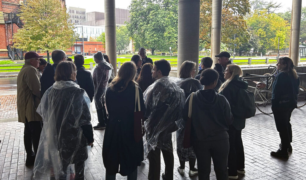 People in ponchos heading to into the rain with buildings in the background.