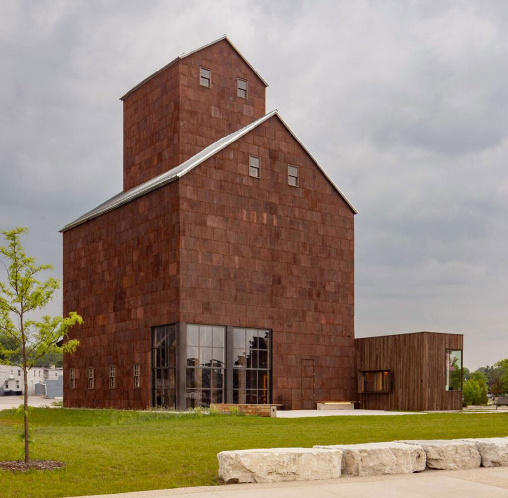 Tall wood shingled building with layered pitched roofs.