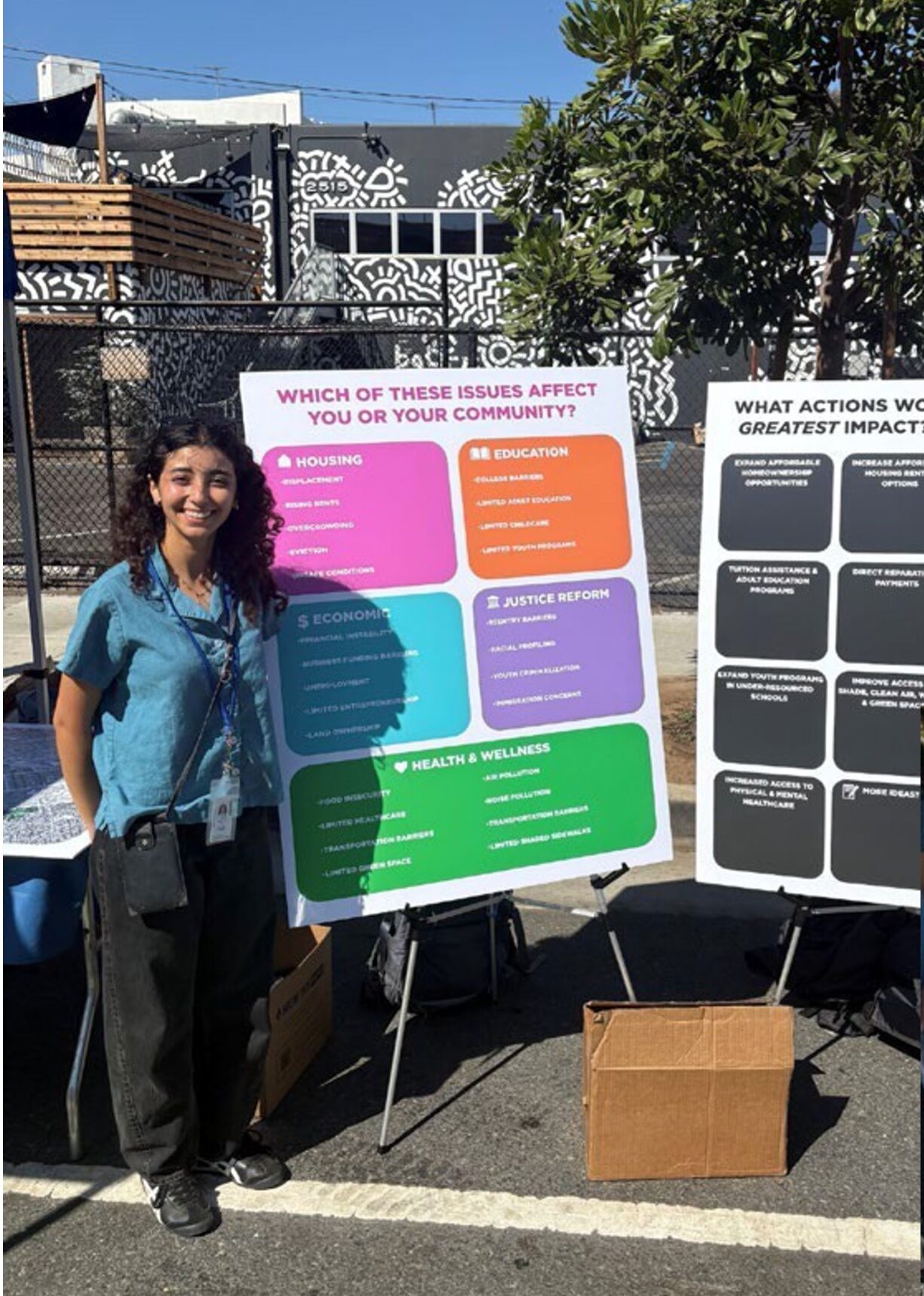 a woman stands in front of two posters outside on a sidewalk