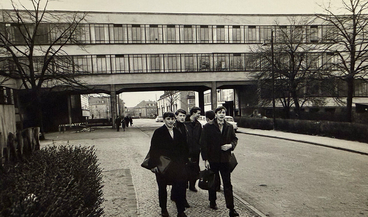 Students in front of a window-lined building that stretches across a street