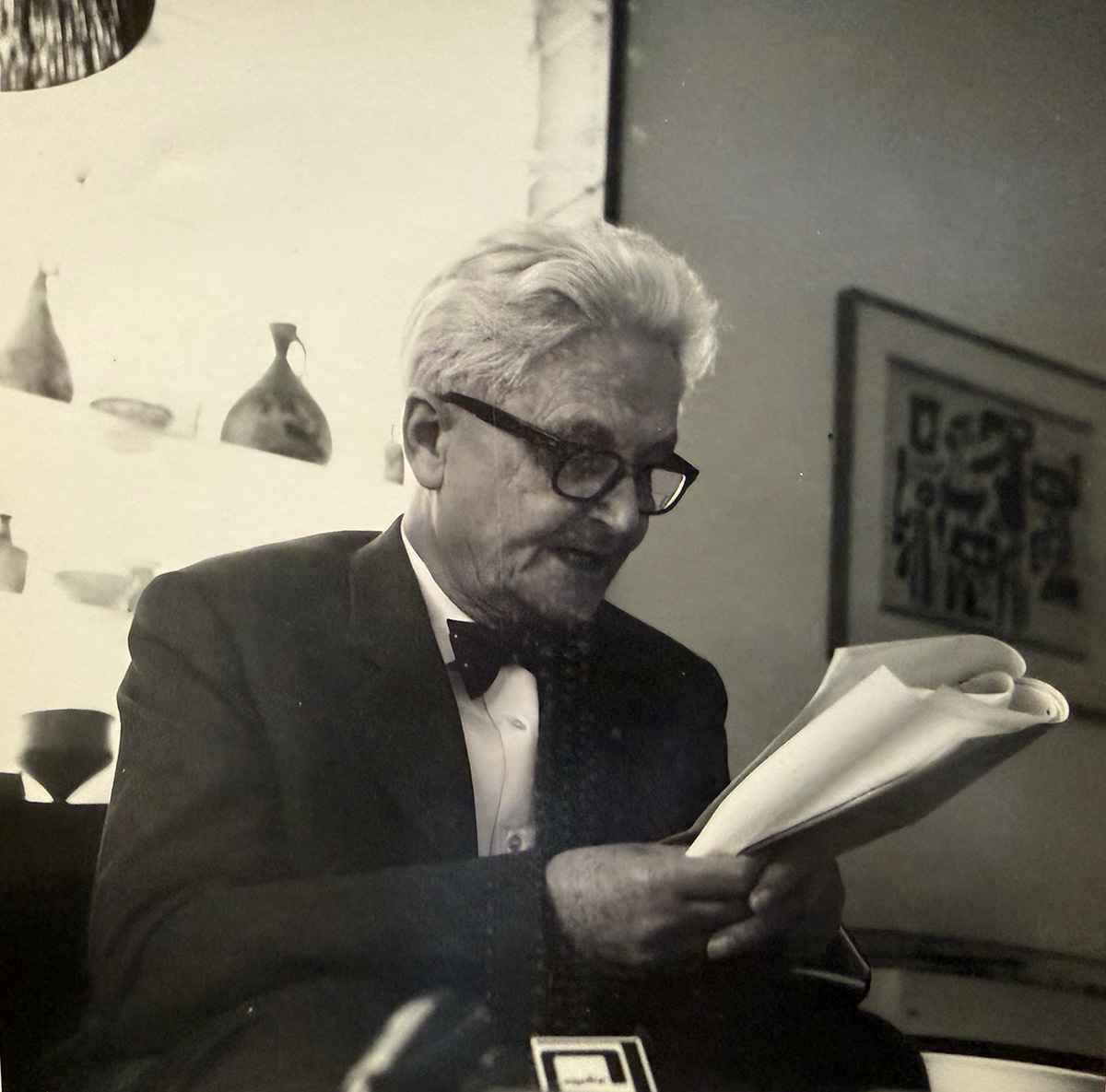 a man with white hair and glasses reads a newspaper