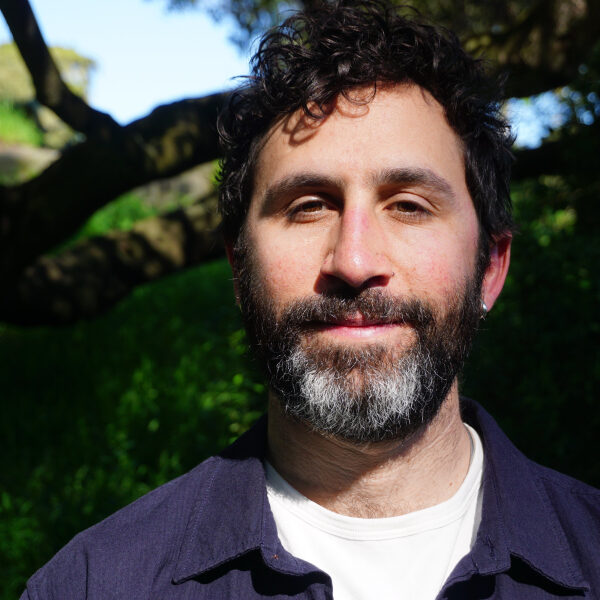Daví Parente Schoen pictured in a navy shirt with trees and a blue sky in the background.